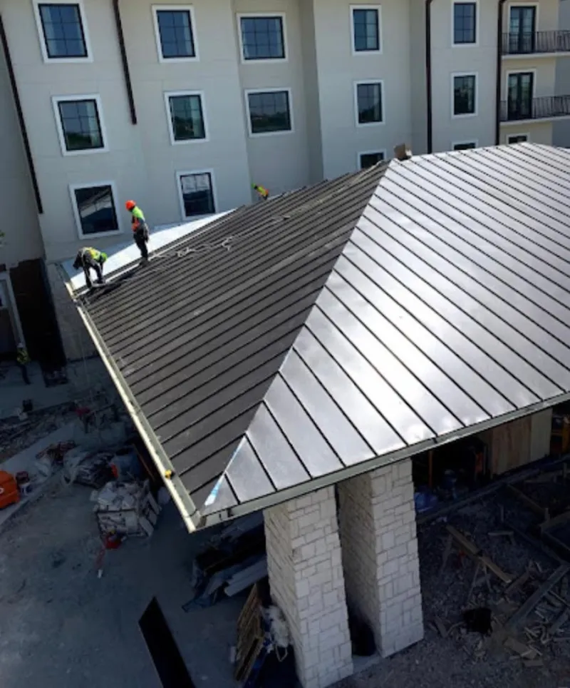 Crew installing standing seam metal roof panels on a commercial project in Apple Valley